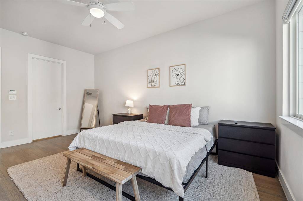 The luxurious primary bedroom is a private retreat, featuring hardwood flooring, oversized windows, and a spacious layout.