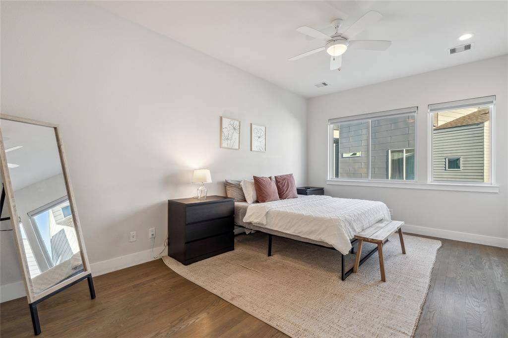 Large windows allow sunlight to pour in, creating an airy and inviting atmosphere. The high ceilings and neutral-toned walls enhance the sense of openness, while sleek wood flooring adds warmth and sophistication.