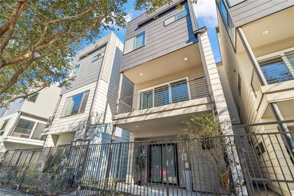 The architectural design is clean and geometric, with large windows and a private second-floor balcony that enhance the home’s modern aesthetic.