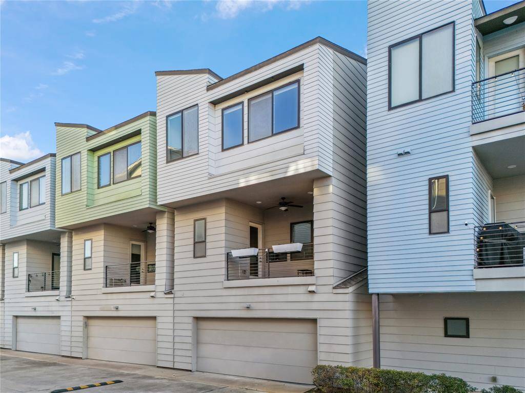 The rear exterior of this modern three-story townhome showcases a sleek, contemporary design with horizontal siding in a neutral color palette, creating a clean and uniform look.