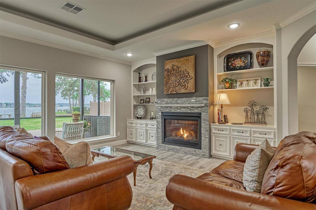 Custom built-ins flank the gas log fireplace, which features eye-catching designer tile for a stylish touch. The open shelving is ideal for showcasing photos and décor, while the lower cabinets offer convenient hidden storage.