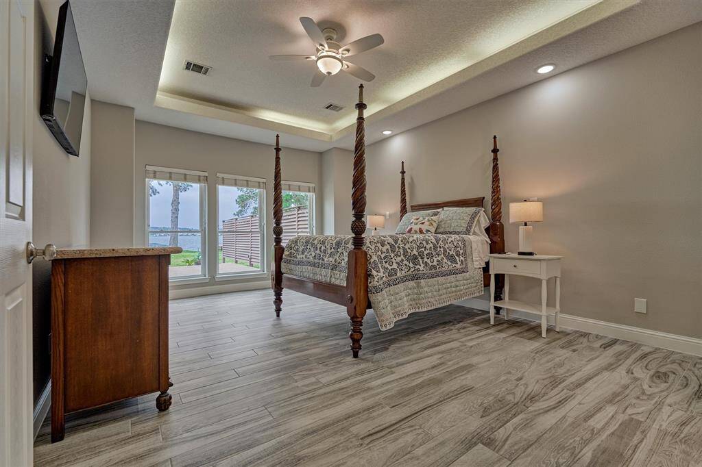 The primary bedroom is spacious enough to accommodate a king-size bed, a cozy sitting area, and multiple furniture pieces. The wood-look tile flooring continues here, adding warmth and continuity to the design.