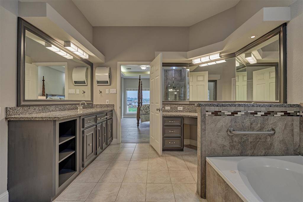 The en-suite primary bath features dual sink and vanity areas, each with ample storage drawers, built-in shelving, and expansive mirrors for a functional yet luxurious feel.