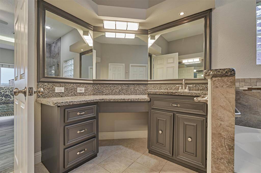 The vanity on the right includes an expansive three-sided mirror, an open area for a stool, and a built-in sink, offering both comfort and convenience for daily routines.