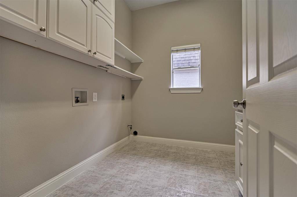 The generous laundry room features a combination of closed cabinetry and open shelving, providing flexible storage options. There's also plenty of room to accommodate a refrigerator or freezer, and an extra pantry adds even more space for organization and everyday convenience.
