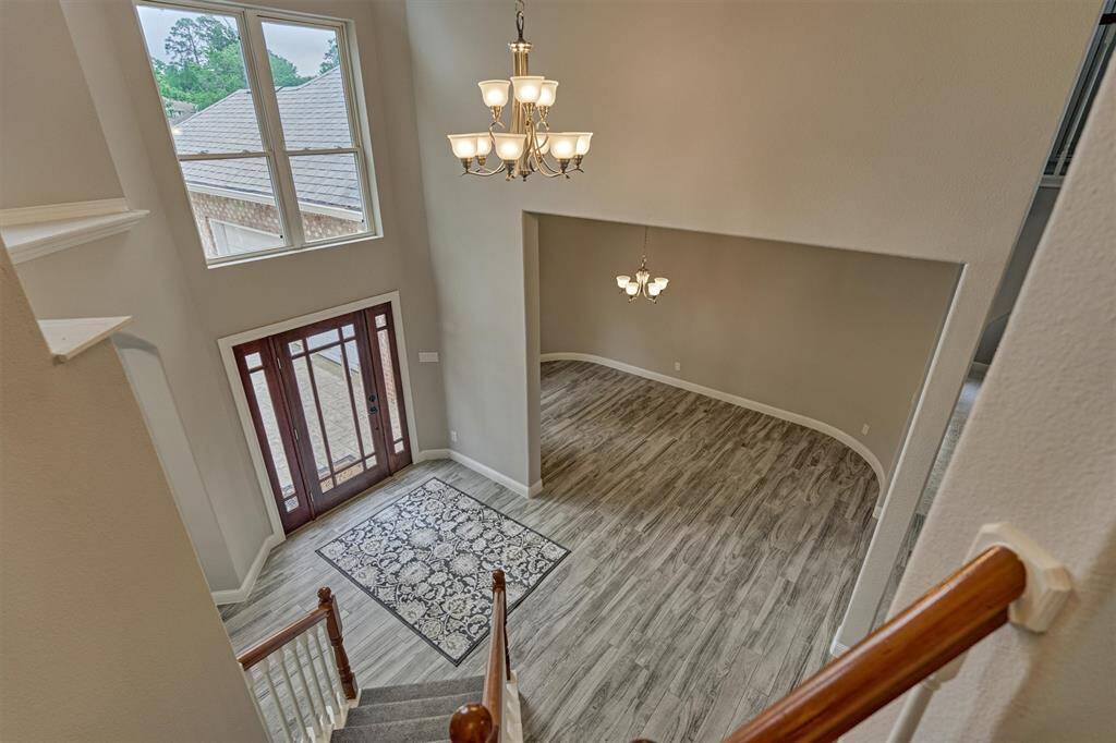 A view overlooking the entry foyer and formal dining area highlights the impressive ceiling height, showcasing the grandeur of the space.