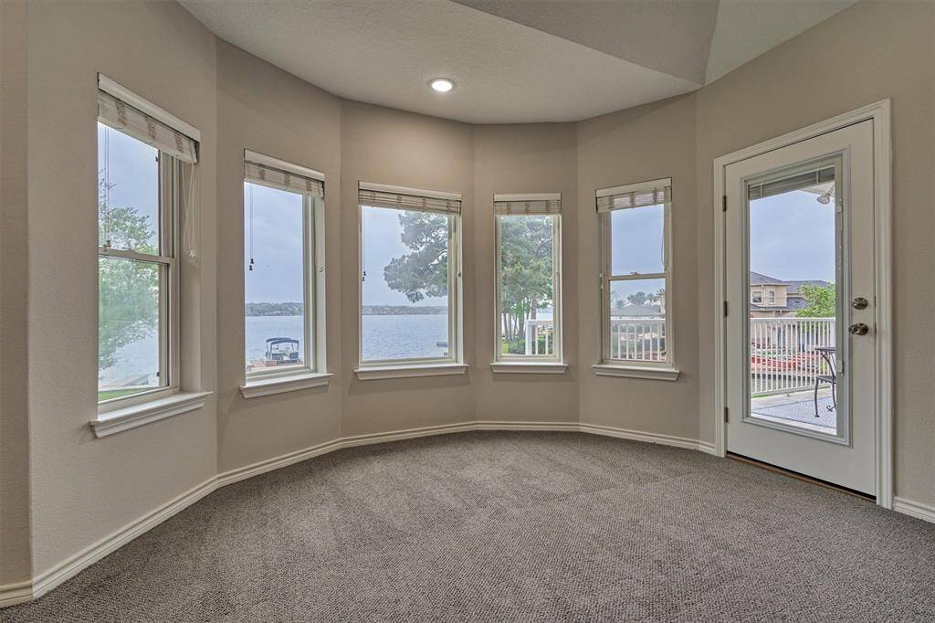 The first guest bedroom delivers a true wow-factor with an impressive curved wall of windows overlooking the lake. A door leads to the second floor balcony for use of the outdoor space.