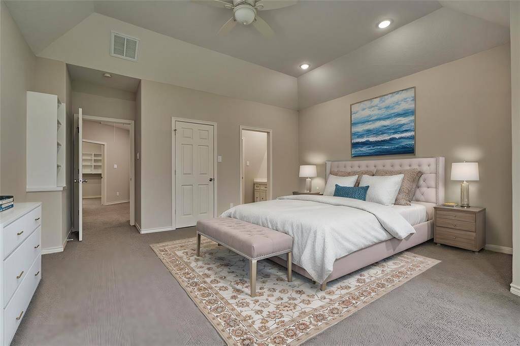 This guest bedroom includes a spacious walk-in closet with built-in storage and a private sink area that connects to a Jack and Jill bathroom. Virtually staged to show furniture placement.