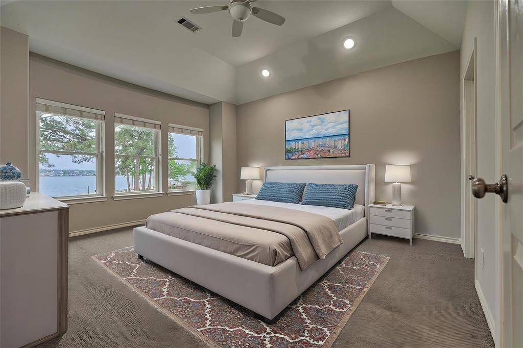The third guest bedroom showcases expansive windows with picturesque views of the lake and includes a private en-suite bath. With its generous layout and serene setting, this room could easily serve as a second primary suite if desired. Virtually staged to show furniture placement.