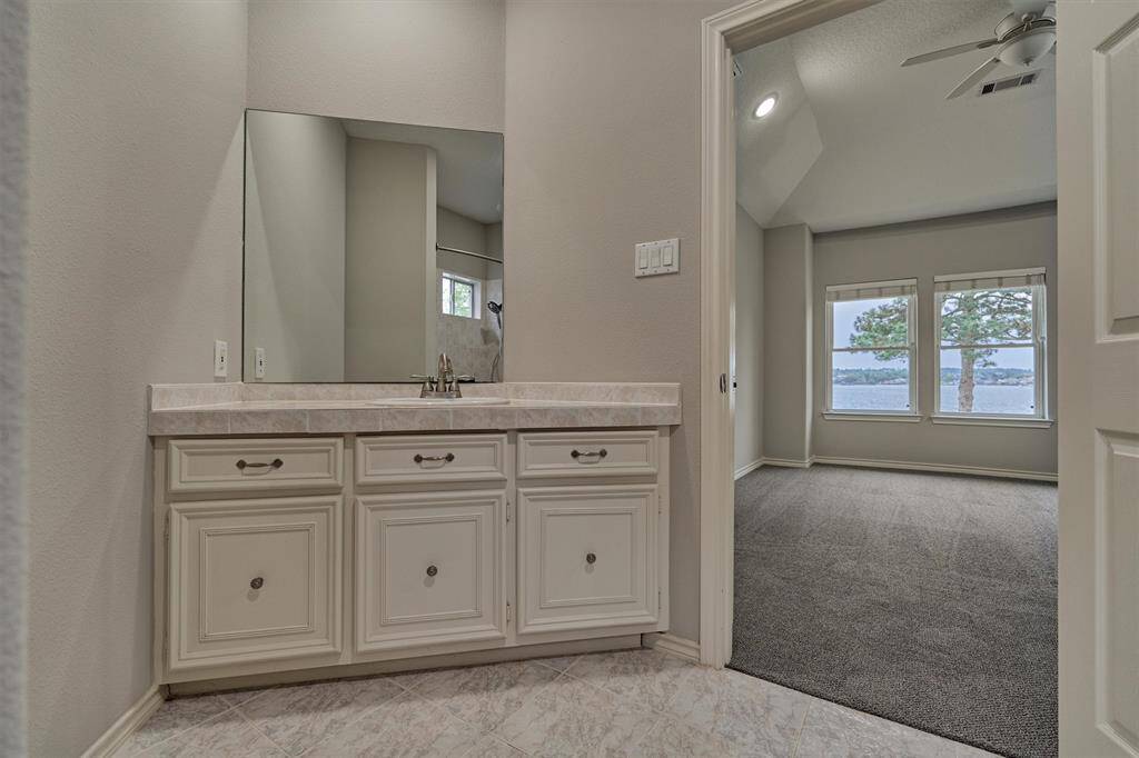 The sink area of the full en-suite bath includes cabinets and drawers, providing plenty of space to keep essentials neatly organized.