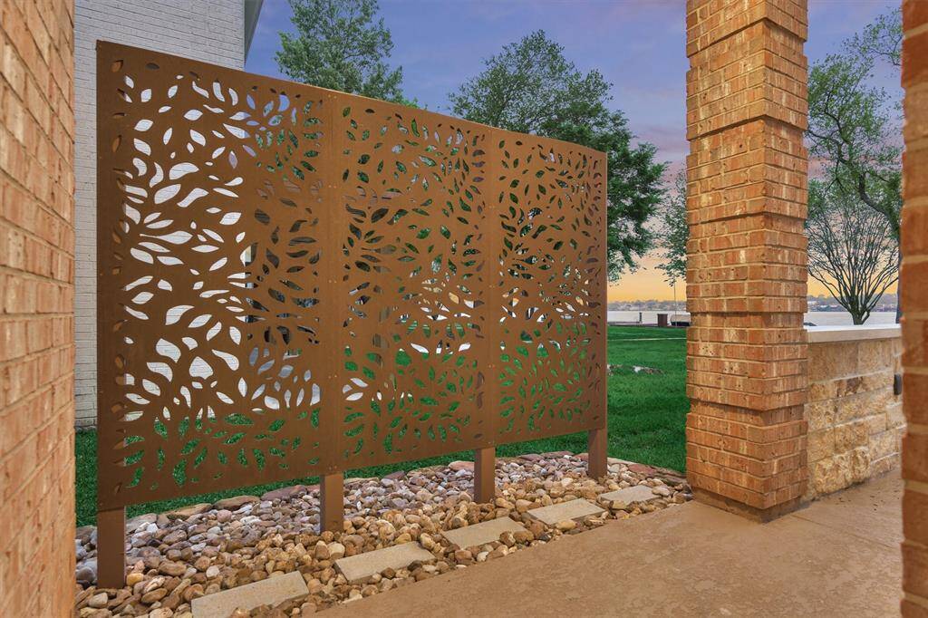 Just off the breakfast area and kitchen, a side porch leads to the back patio. A distinctive privacy screen adds both seclusion and an artistic flair to the side of the home, enhancing the outdoor living experience.