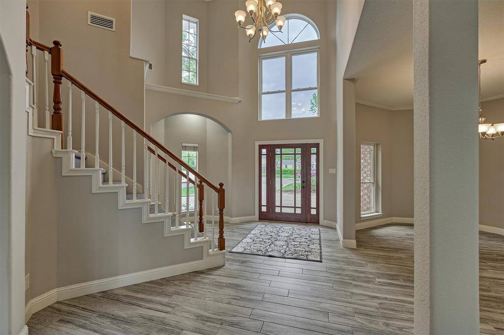 Another view of the light-filled entry highlights its bright and welcoming atmosphere. To the right, the formal dining room provides an elegant space for gatherings, while a decorative niche to the left adds a tasteful accent to the foyer.