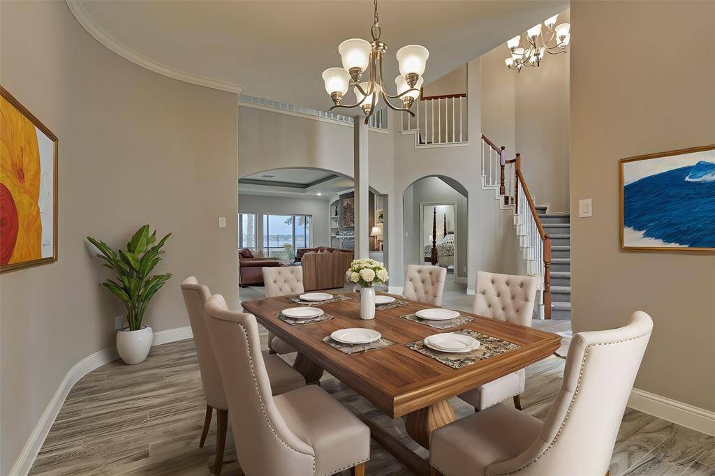 The formal dining area offers a blend of elegant architectural details and serene lake views beyond, creating a refined and picturesque dining experience. Virtually staged to show furniture placement.