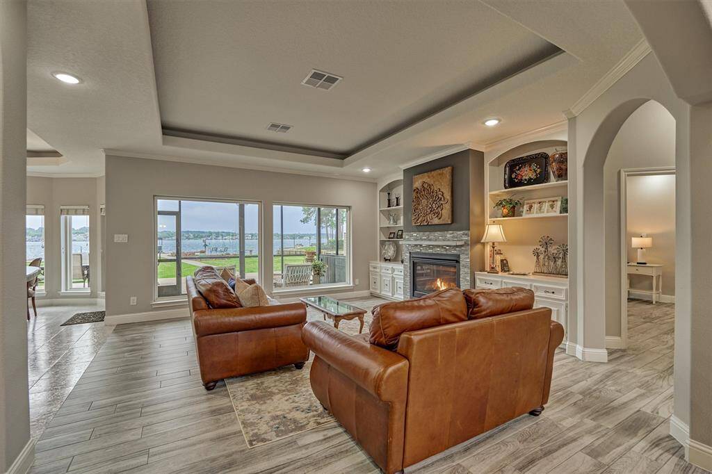 Expansive windows in the living room frame picturesque views of the lake and backyard. A tray ceiling adds architectural interest and enhances the open, airy feel of the space.