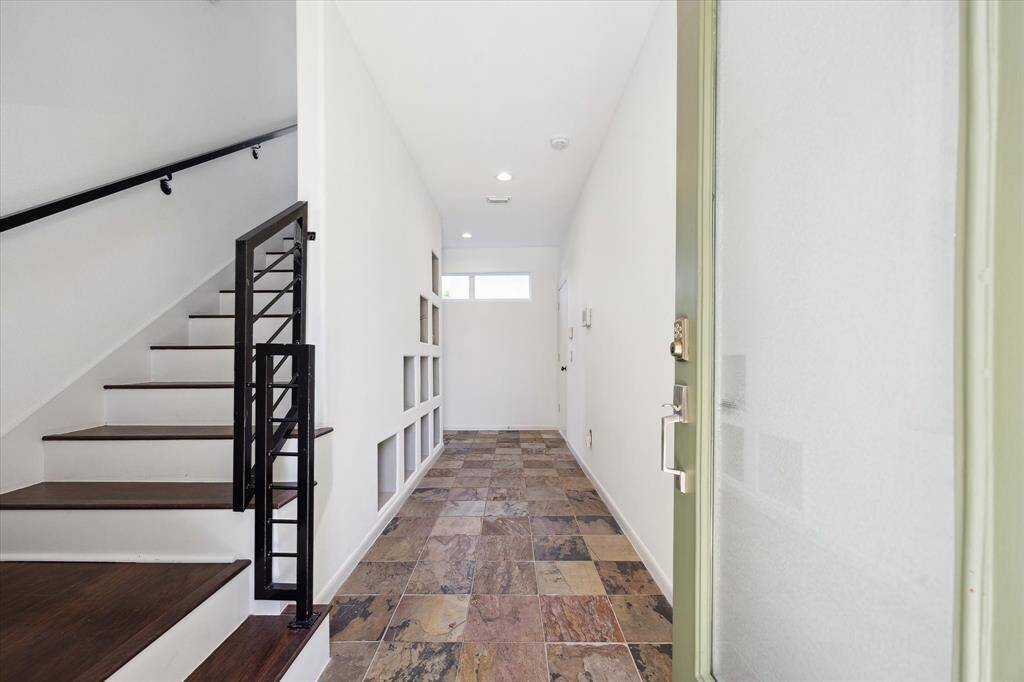 Welcome guests through a stylish ground floor entry, featuring slate tile flooring and a built-in wall niche display that adds both charm and function. Clean lines and natural textures set the tone for the modern design found throughout the home.