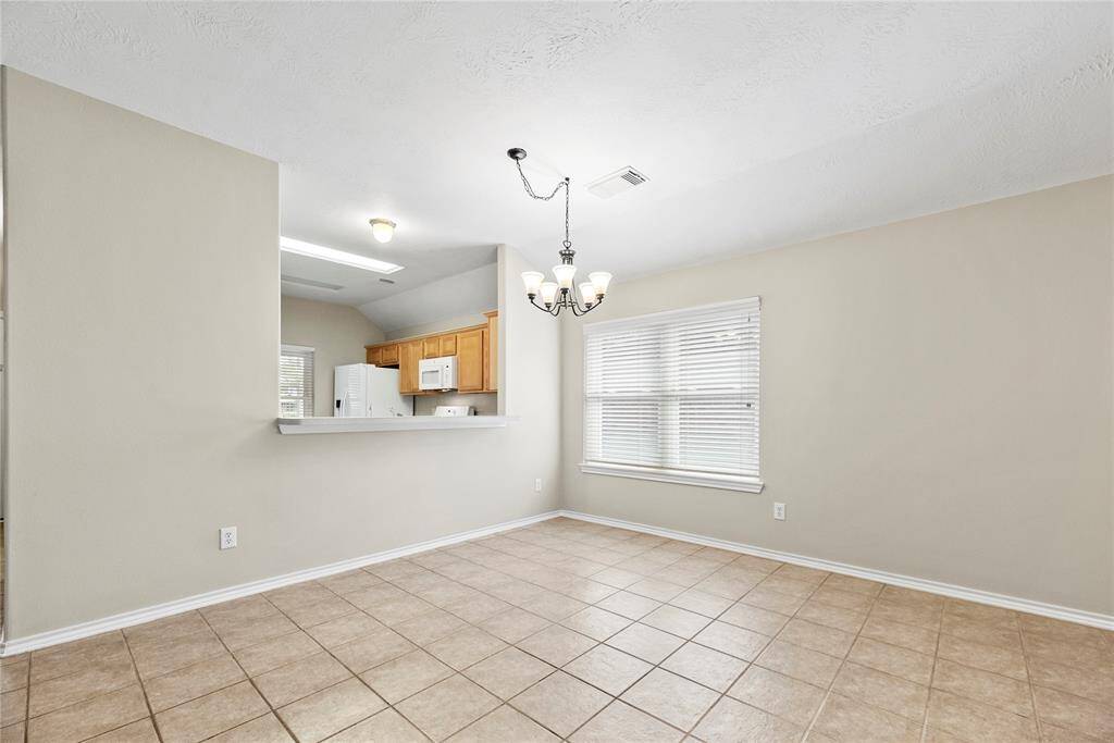 The dining area is ideal for a full-sized table and features easy care tile floors, a large bright window, and overhead chandelier.