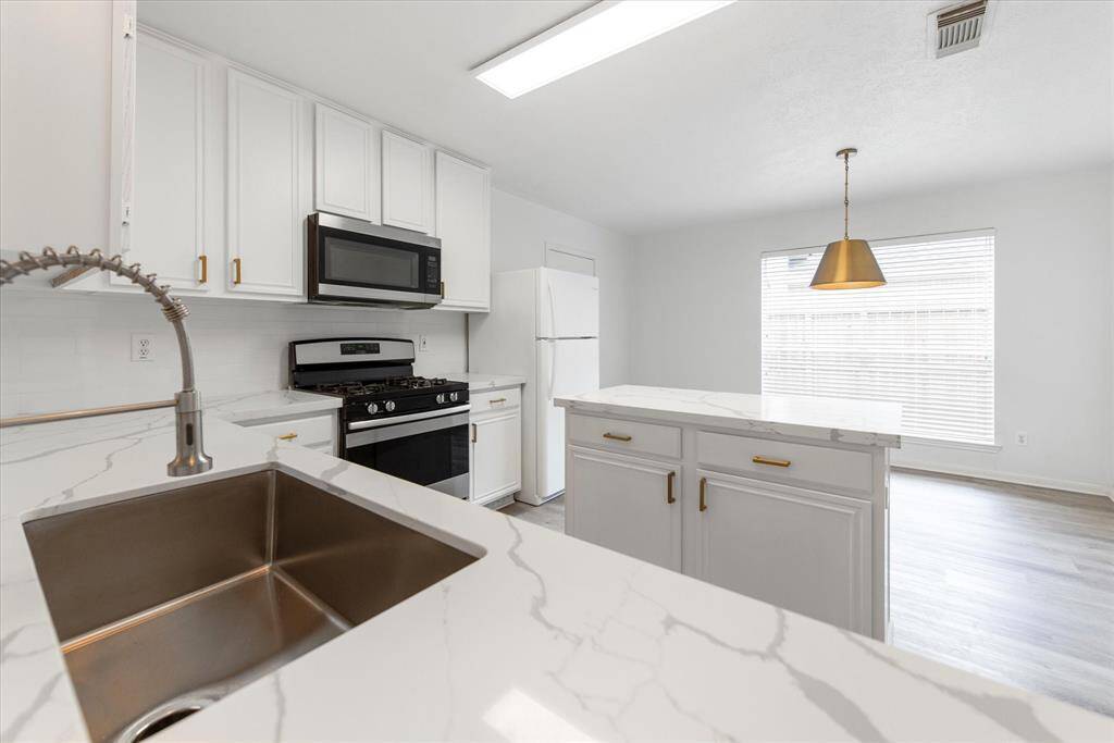 Enjoy Quartz countertops, sparkling undermount sink, painted cabinetry with updated hardware and gorgeous black and gold fixtures in the kitchen.