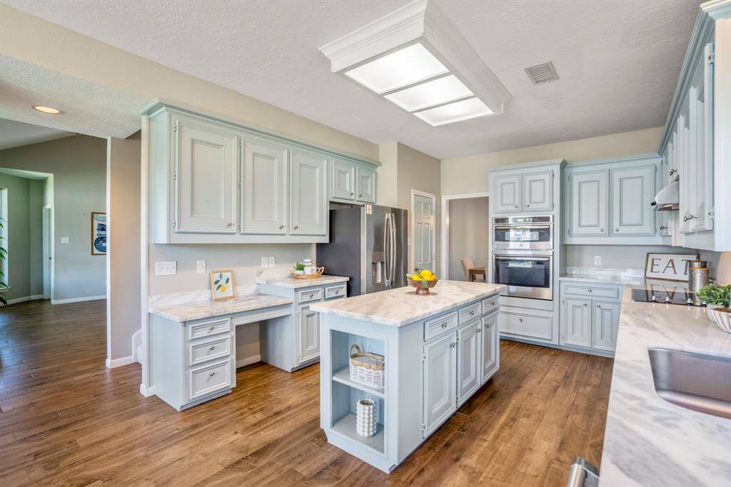 The white marble countertops gives a natural feel that echoes the wood look tile flooring and cabinetry.