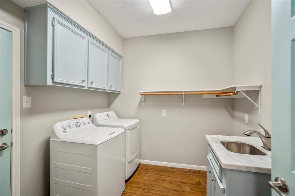 The laundry room offers lots of additional storage space, with upper cabinets, a stainless steel sink, and marble top which is convenient in a lake house.