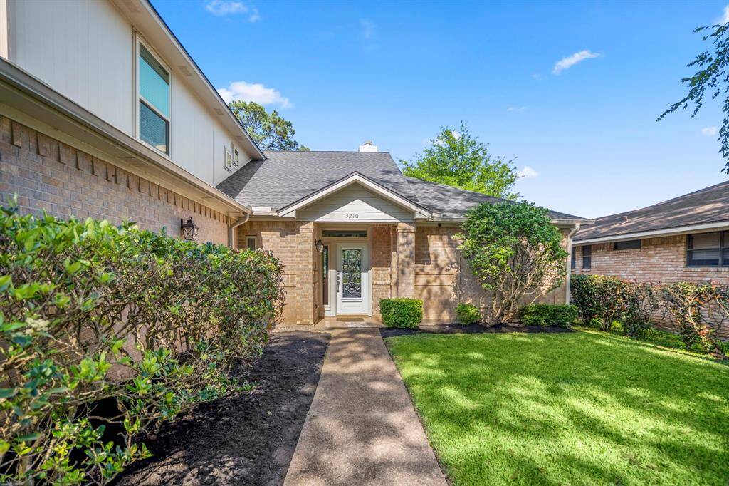 Established landscaping flank the walkway to the entrance of the home.