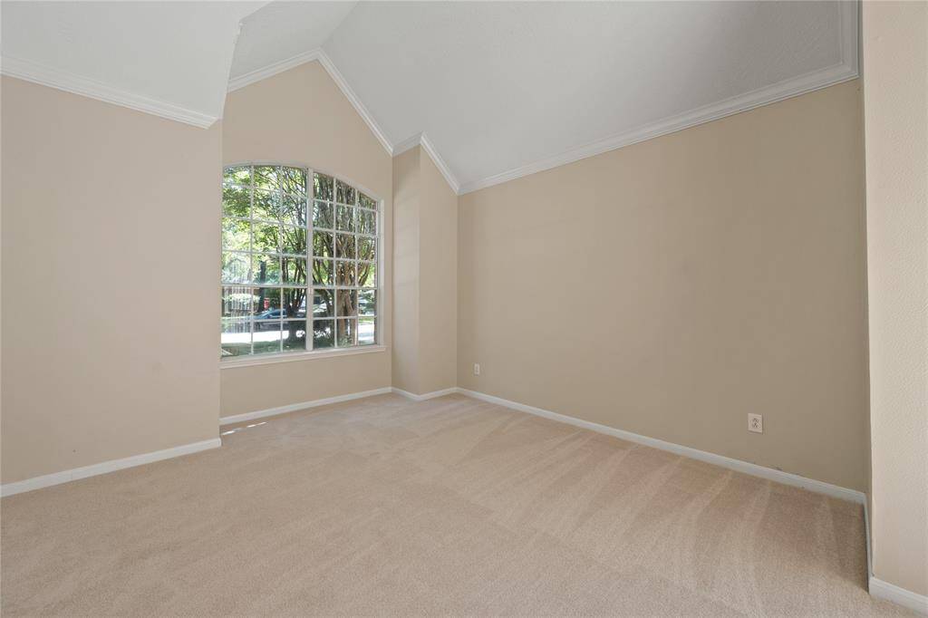 This living area features high vaulted ceilings with a large arched window, allowing natural light to fill the space.
