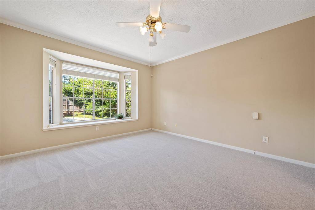 Bright primary bedroom with a large bay window inviting natural light. Features ample space for furniture arrangement.