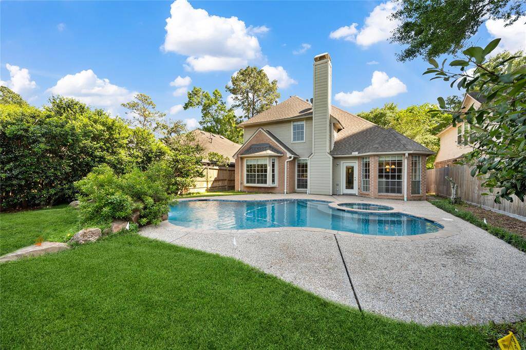 This inviting backyard features a spacious swimming pool and hot tub, surrounded by well-maintained greenery and a privacy fence.