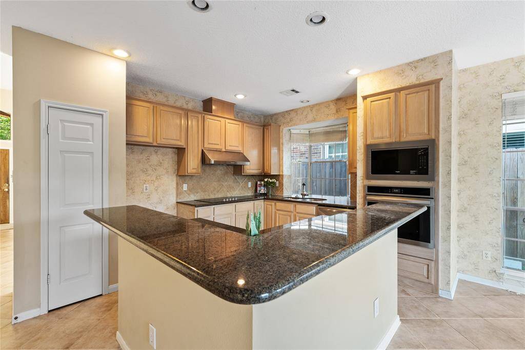 Kitchen features a spacious layout with granite countertops, ample wooden cabinetry, and built-in appliances.
