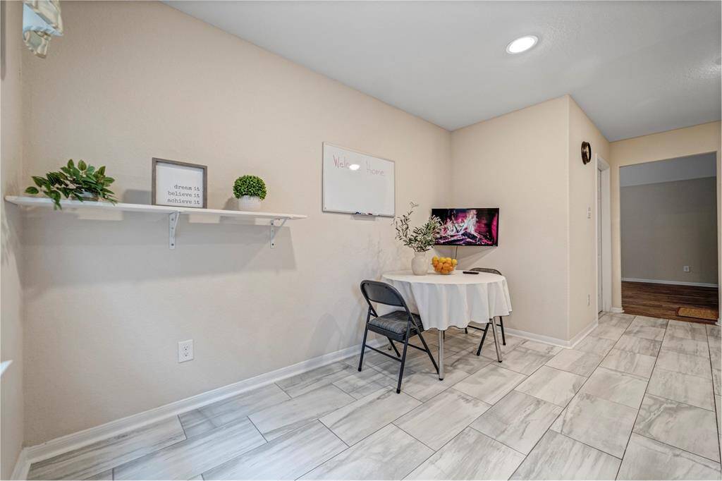 A bright dining area with tiled flooring, neutral walls, and recessed lighting.