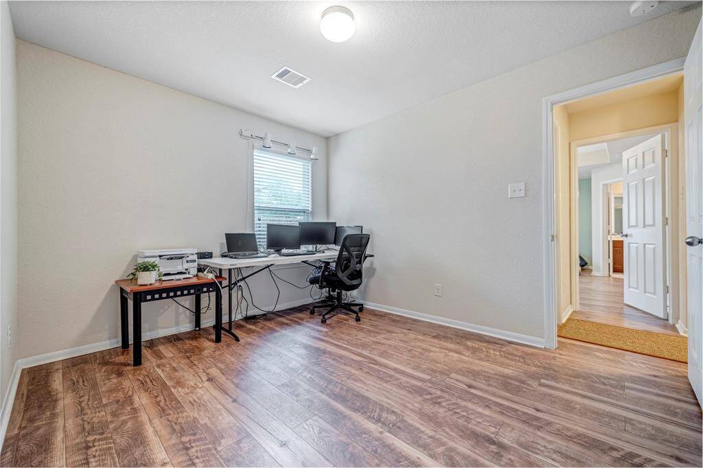 Second bedroom is used as a bright, spacious home office with wood like flooring, neutral walls, and a window providing natural light. Offering a clean and functional workspace.