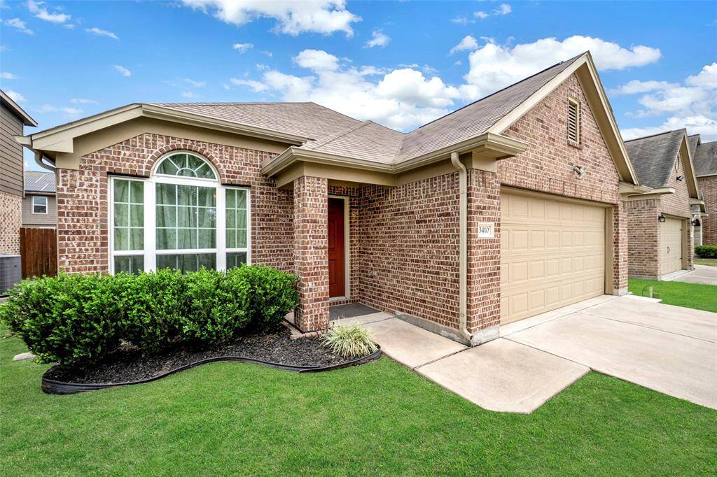 This charming home features a well-maintained lawn, arched windows, and a two-car garage. It offers a welcoming entryway with a modern design, perfect for comfortable living.
