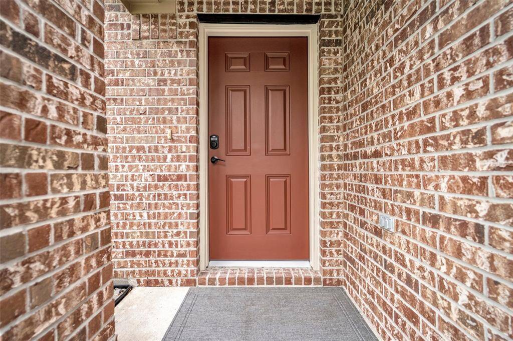 A welcoming front entryway with a warm-toned brick exterior and a solid, red-brown door.