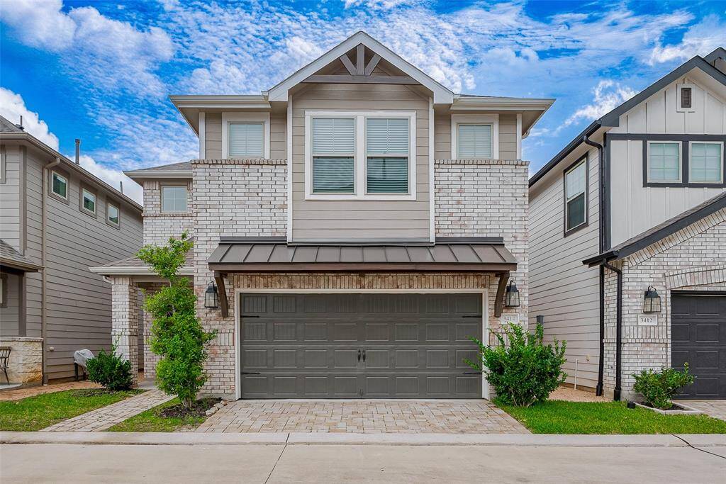 A welcoming brick exterior combines classic charm with modern ease, featuring a two-car attached garage and a recessed entry tucked thoughtfully to the side beneath a covered space for added privacy and shelter.