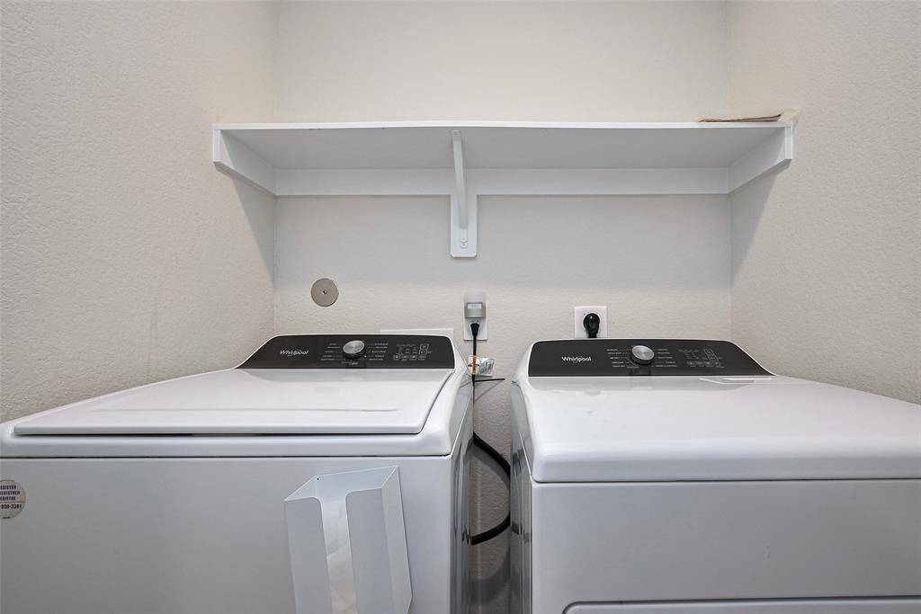 The laundry space is neatly arranged with a built-in overhead shelf—ideal for storing essentials and keeping the area tidy and efficient.
