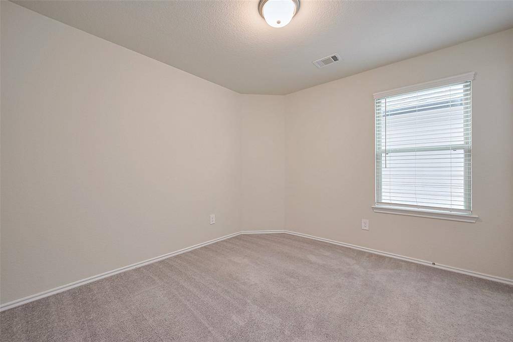 Soft carpeting and a light neutral palette give this bedroom a calm, restful feel, while a wide window brightens the space with natural light.