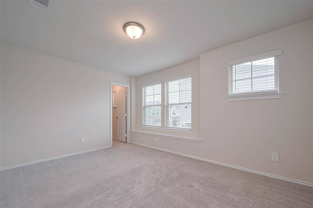 This generously sized bedroom is bright and welcoming, with plush carpeting underfoot, large windows, and a full entry closet offering ample storage.