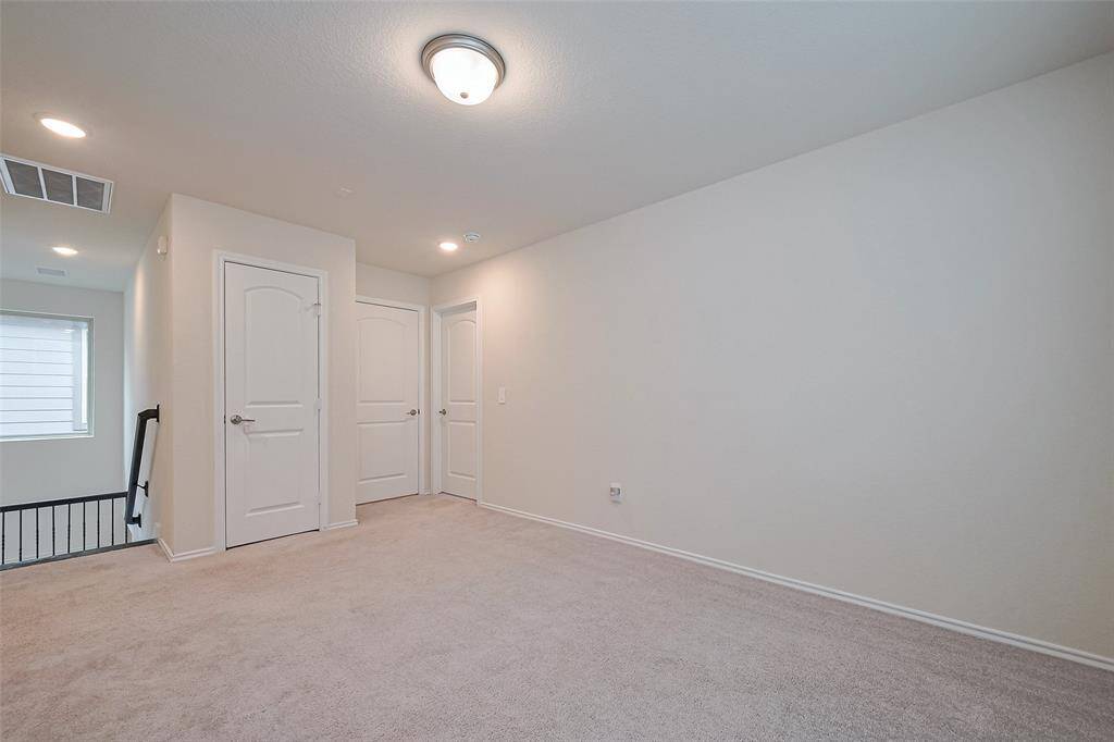 Spacious and carpeted, the upstairs landing connects the upper rooms with ease and is well-lit by a mix of recessed and surface mount lighting, creating a central hub on the second level.