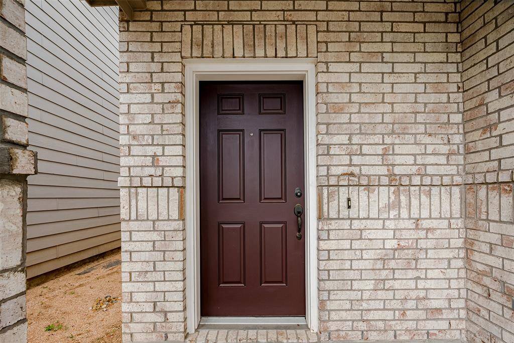This handsome dark wood door makes a striking statement against the soft-hued brick, highlighting a thoughtful blend of tone and texture at the entry.