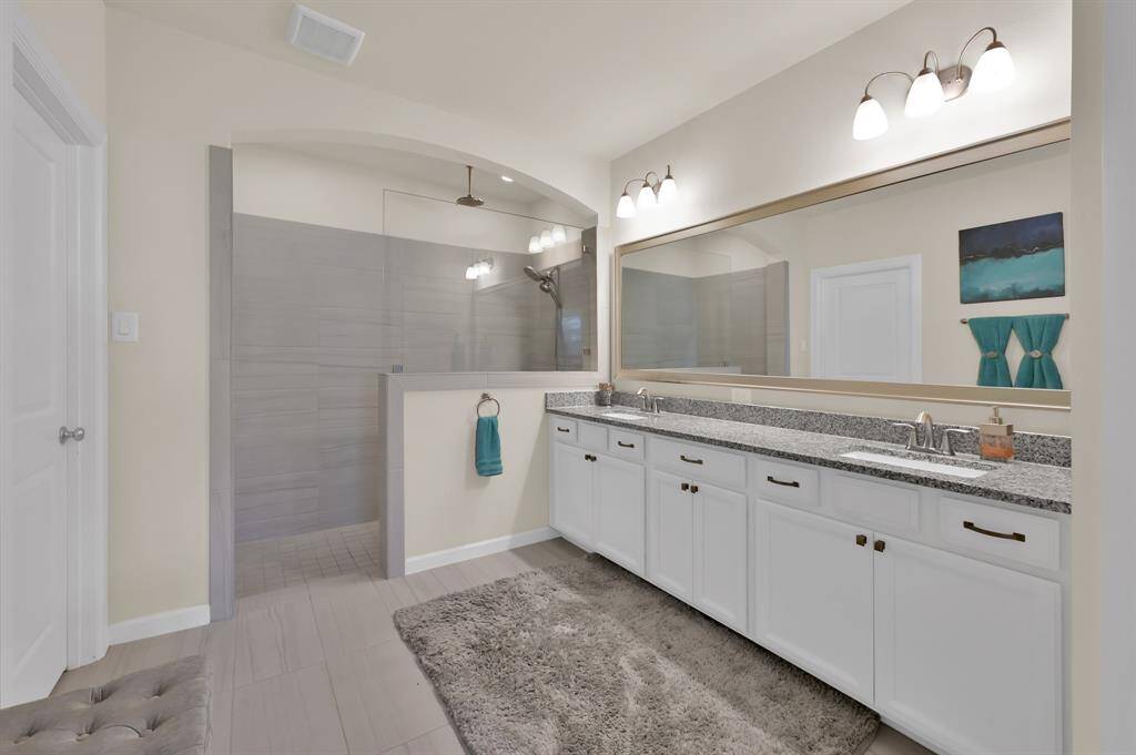 The primary bathroom features a generously sized shower with dual shower heads. The rain head will have you feeling like you're in a spa retreat. Granite countertops, dual sinks, plentiful cabinetry, and stylish fixtures all around... this is the bathroom you deserve!