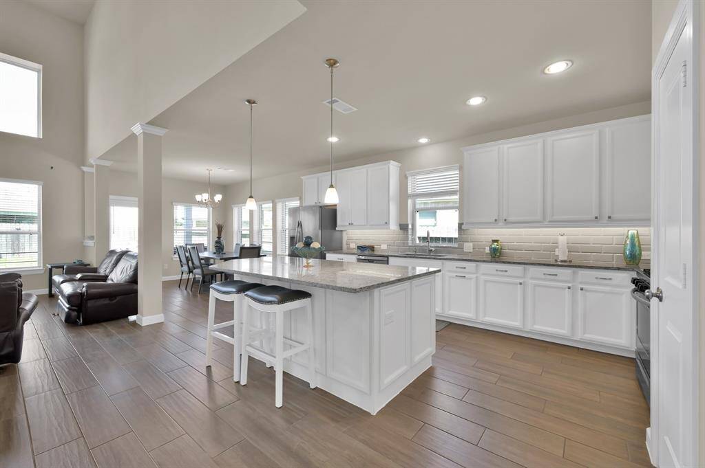 If you head down the hall you'll meet your elegant future kitchen. This entertainer's kitchen is complete with white cabinetry, pendant and recessed lighting, a stylish and modern backsplash, and a large island to set this kitchen apart from the competition.