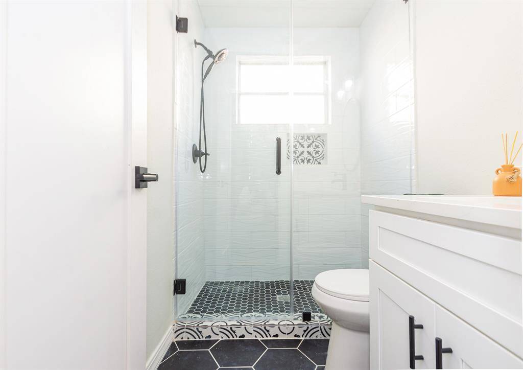 Updated hallway bathroom featuring a sleek tile walk-in shower and elegant quartz countertops