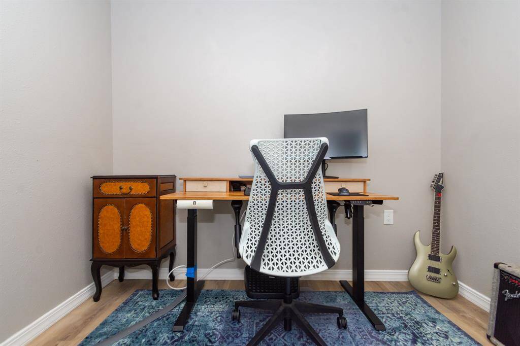 Private office with sleek laminate flooring, ideally situated just steps from the primary bedroom—perfect for remote work or a quiet retreat.