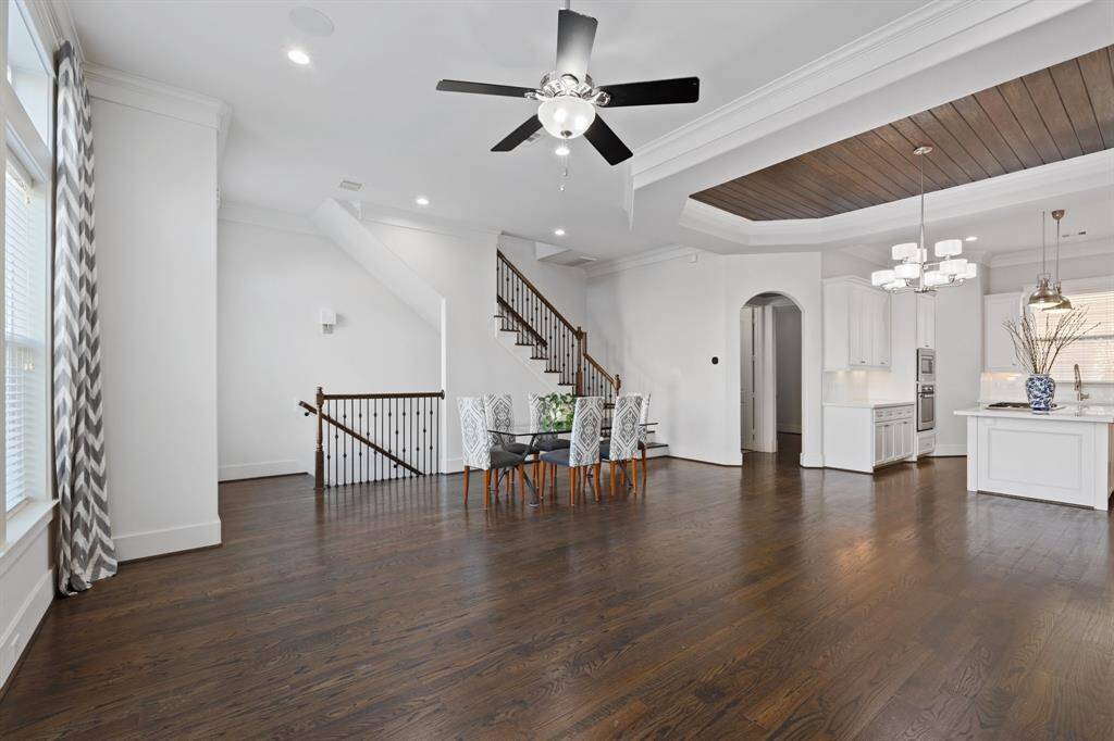 Living room features beautiful flooring, aceiling fan, high ceilings, and large windows.