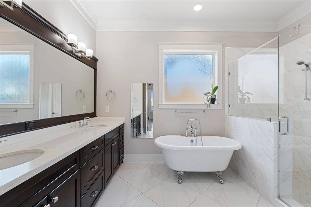 The primary bathroom features tile floors, dual sinks, dark cabinets, clawfoot tub, and walk-in shower with tile surround.