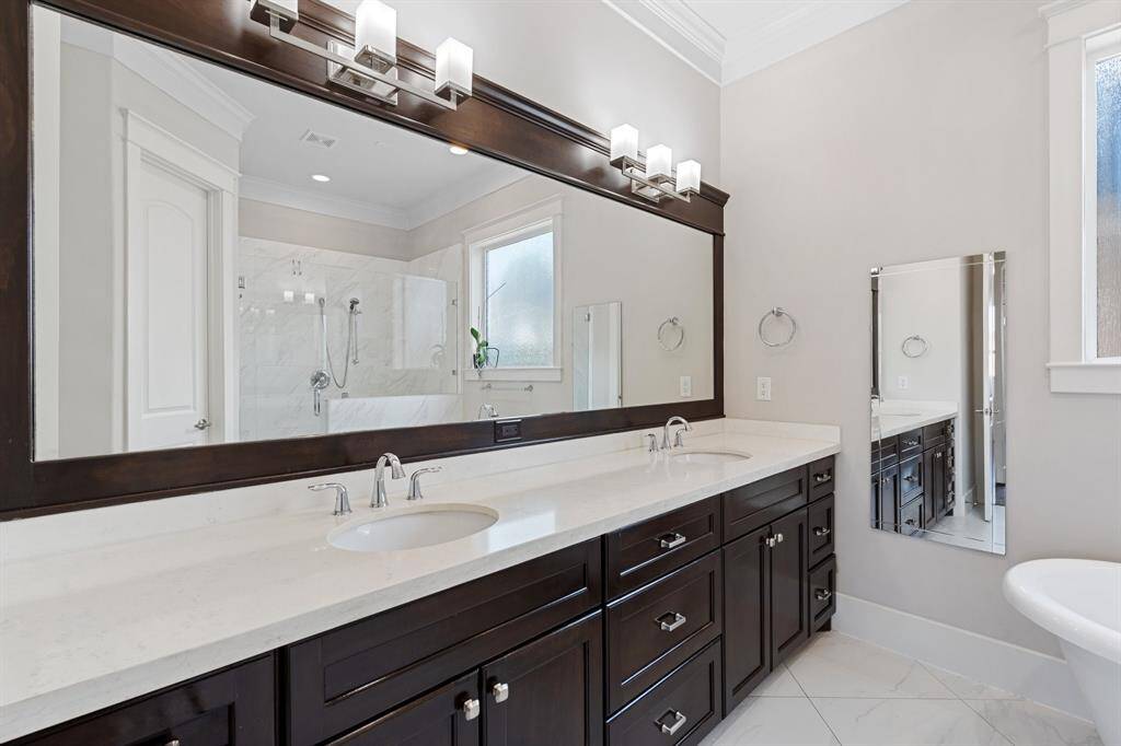 The primary bathroom features tile floors, dual sinks, dark cabinets, clawfoot tub, and walk-in shower with tile surround.