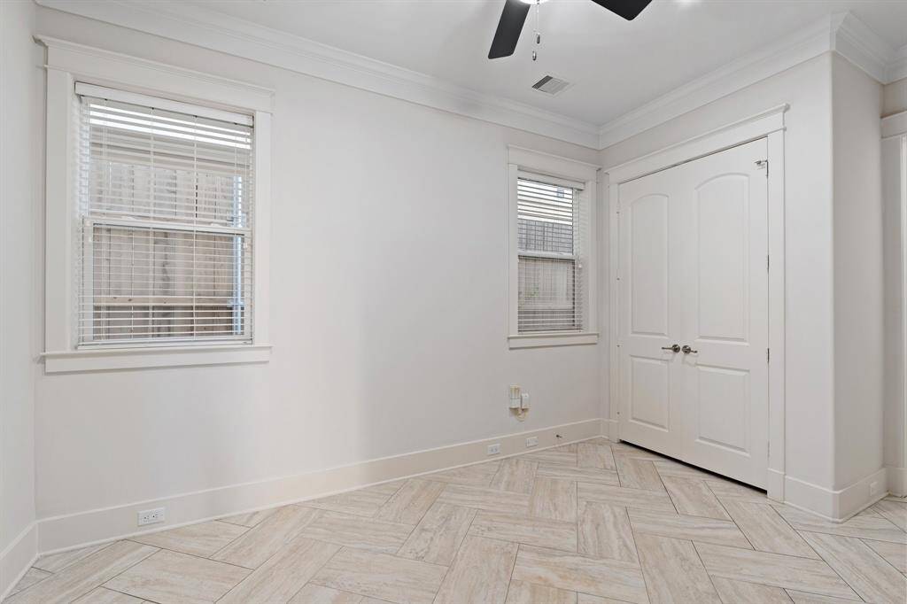 The first floor bedroom features tile floors, large windows, and a ceiling fan.
