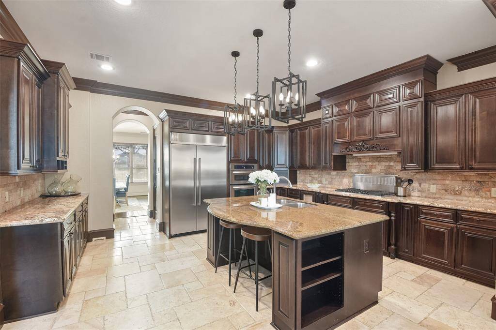 The gourmet kitchen boasts rich wood cabinetry, ample storage, a large center island, stainless steel appliances, and a Reverse Osmosis system.