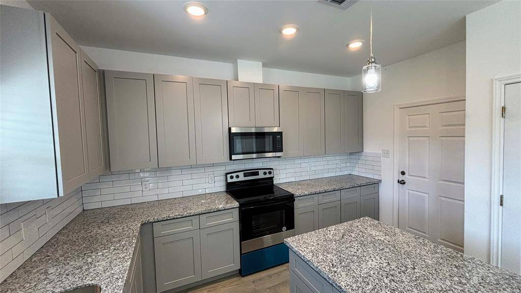 This modern kitchen features granite countertops, ample cabinet space, and a central island.