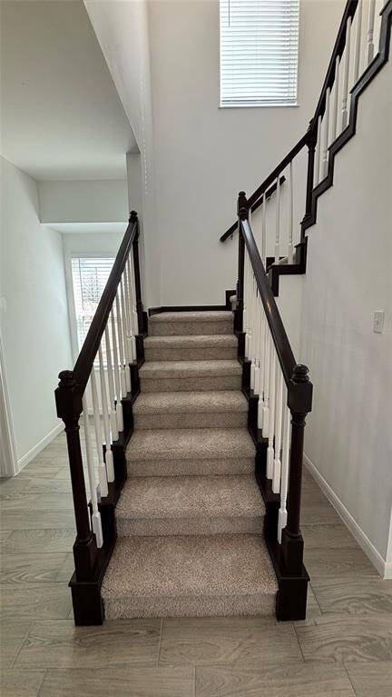 Carpeted staircase with dark wood handrails and white balusters, leading to an upper level.