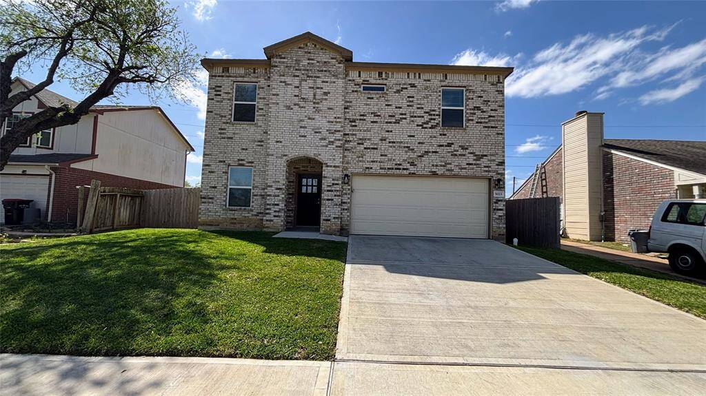 Front of the house with a spacious front yard. The property is fenced and has a mature tree providing shade.